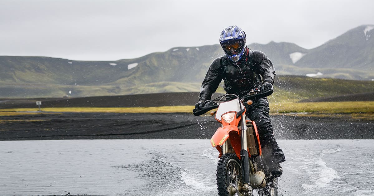 An experienced rider crosses a wetland on an electric dirt bike